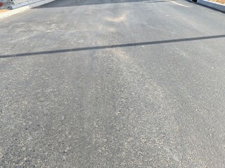 Fototapeta premium Asphalt road, Smooth asphalt road. The texture of the tarmac, top view. Urban landscape road. Close-up horizontal view of new asphalt road