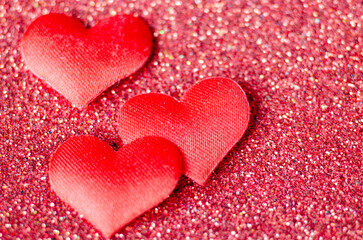 Top view of 3 tiny red hearts on sparkle red background with customizable space for text or wishes.