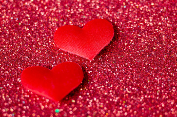 Obraz premium Side view of two tiny red hearts on sparkle red background with customizable space for text or wishes