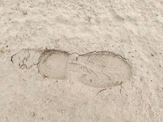 Footstep on sandy Beach, Foot print on Soil. Footprints in the sand on the beach. Top view. Sand in the sand pit, shot from above. Footprints of shoes and sandals on brown sand