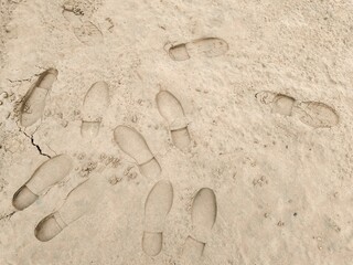 Footstep on sandy Beach, Foot print on Soil. Footprints in the sand on the beach. Top view. Sand in the sand pit, shot from above. Footprints of shoes and sandals on brown sand