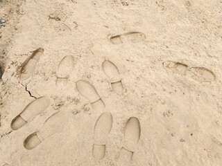 Footstep on sandy Beach, Foot print on Soil. Footprints in the sand on the beach. Top view. Sand in the sand pit, shot from above. Footprints of shoes and sandals on brown sand