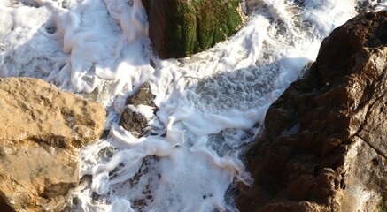 Stones among the ocean foam. Close-up. Freshness. Textures. Top View. Abstract background