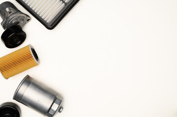 Top view of auto parts, fuel, air and oil filters on white background, tensioner roller. Auto parts replacement concept, auto repair. Copy space.