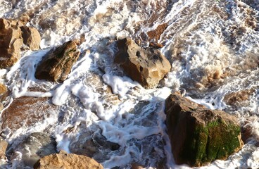 Stones among the ocean foam. Close-up. Freshness. Textures. Top View. Abstract background