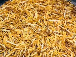Roasted vermicelli noodles in a black frying pan, preparation process for traditional Middle Eastern kadaj dessert.