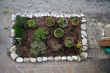 view of a elegant herbal bed framed with stones in a garden