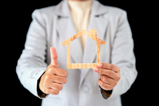 woman wearing suit holding toy house showing stable life dream. woman reveal wooden home symbol for working achievement goal in future. adult business employee having dream house by doing business