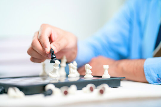 asian office man sitting playing checkers to improve brain. adult in business uniform playing chess for better work. office man focus on developing smart thought and effective work using chess board