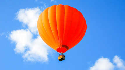Naklejka premium Orange hot air balloon soaring through a clear blue sky with puffy clouds, evoking a sense of adventure and freedom