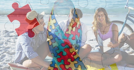 Image of colourful puzzle pieces ribbon over happy friends at summer beach party