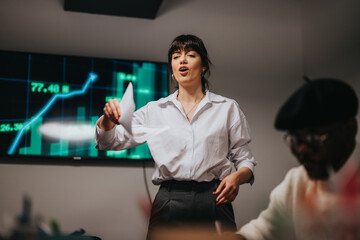 A confident woman explaining financial data to colleagues, highlighting charts and trends on a...