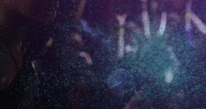 Female singer wearing headphones singing in music studio, glowing particles swirling by microphone