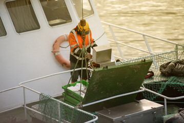 Sailor, manipulating crane controls to unload the load of fish