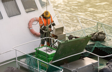 Sailor, manipulating crane controls to unload the load of fish