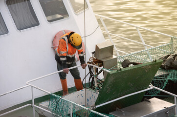 Sailor, manipulating crane controls to unload the load of fish