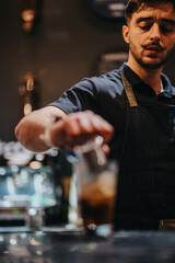 A skilled bartender creates a refreshing beverage with precision at a stylish cafe bar.