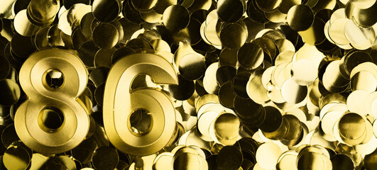 Golden number eighty-six 86 candle on shiny yellow confetti background. Festive backdrop for eighty-sixth birthday, anniversary, or celebration. Bright greeting card with space for text.