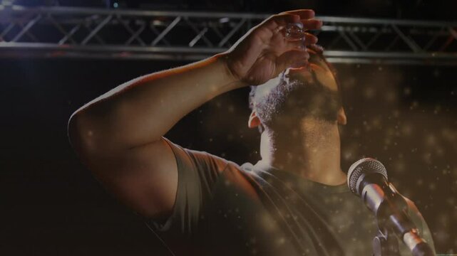 man sprinkling golden particles into mic on music stage, blending live action with animated data