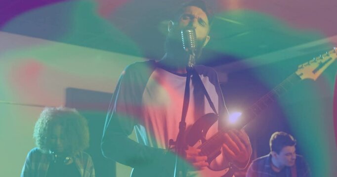Bearded singer playing electric guitar under music stage lights, with animated sound bars rising