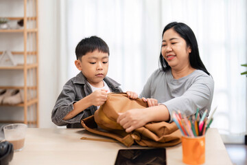 Obraz premium Back to School and Preparation. A mother helping her son pack his backpack for school.