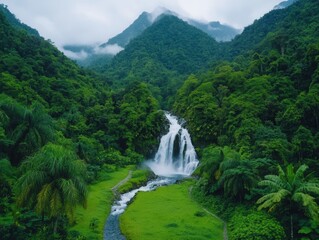 Lush green valley with a cascading waterfall surrounded by vibrant tropical foliage and majestic mountains