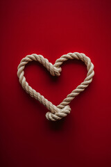 Twisted rope arranged as heart on red backdrop—ideal for Valentine’s Day, relationships, unity, or nautical concepts.