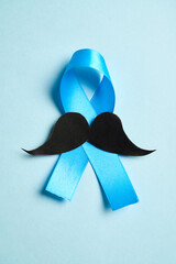 Blue ribbon with mustache supporting prostate cancer awareness month and men's health