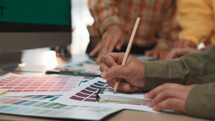 A group of diverse designers collaborates in a bright workspace, using color samples and sketching tools to brainstorm creative ideas and innovative projects. SACTR