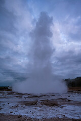 Strokkur geyser steaming aftermath. Vapor clouds drift skyward. Earth stained by sulfur and minerals.
