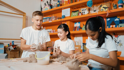 Happy diverse highschool student modeling clay at pottery workshop. Cute children with mixed raced...
