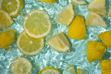 Refreshing turquoise citrus background with floating yellow lemon pieces