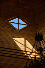 Sunlight streams through a diamond-shaped window in a wooden church interior.