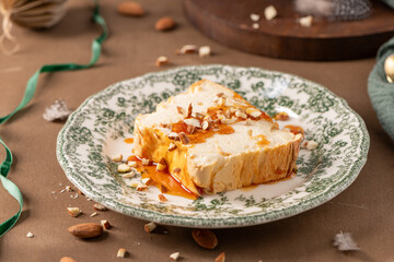 An angled top-down shot showcases a slice of traditional caramelized egg white pudding known as molotof or molotov, generously drizzled with golden syrup and sprinkled with almond pieces