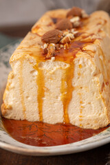 A detailed close-up captures a traditional caramelized egg white pudding known as molotof or molotov, generously drizzled with rich caramel syrup and garnished with whole and chopped almonds