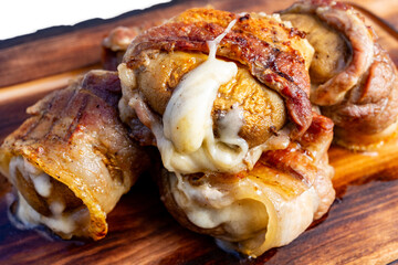 Savory meat rolls filled with melted cheese on a wooden platter