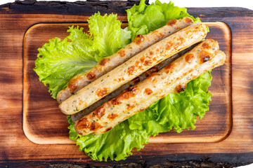 Grilled sausage links served on fresh lettuce with a wooden platter