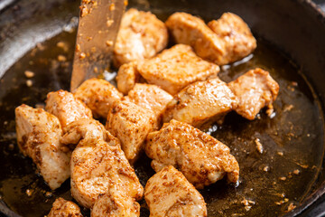 Chicken fillet pieces are fried in a frying pan in sauce