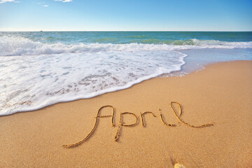 April word written on sea sand shore beach at day.