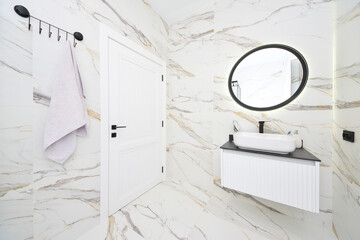 White bathroom with round mirror and bold black details.