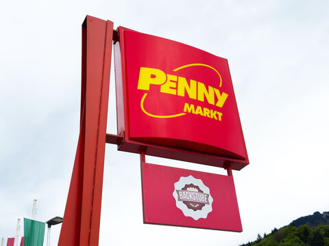 Penny markt store sign in urban setting with bright red colors and cloudy sky background