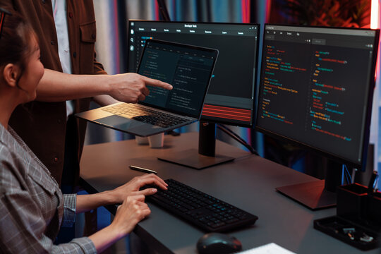 Serious of IT developers discussing intelligent website development coder system running data online two screens with laptop showing information network at neon light room at modern office. Infobahn.