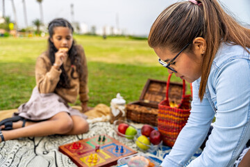 Naklejka premium Mother and daughter enjoying picnic and playing pachisi on mother's day
