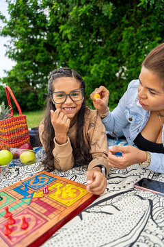 Mother and daughter playing parcheesi outdoors for mother's day celebration