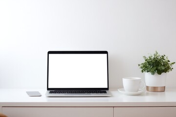 minimalist workspace setup on clean white desk featuring laptop open with blank screen cup of steaming coffee nearby
