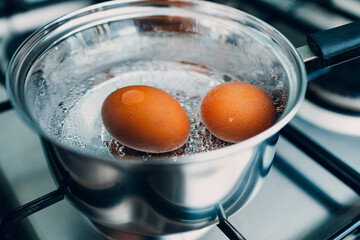 Saucepan stainless steel with boiling eggs breakfast in a water on a gas stove.