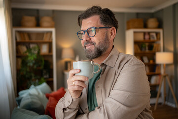 Smiling bearded man enjoying relaxing morning coffee at home