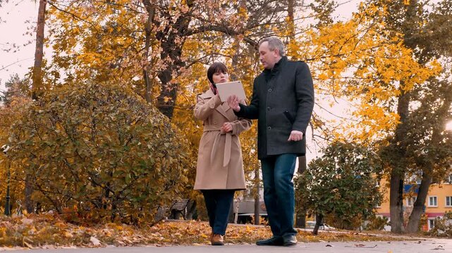 Successful company employees discuss business ideas at meeting in park. Man and woman company employees discuss business idea at meeting. Meeting with company employees to discuss business ideas