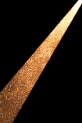 Golden spotlight illuminating dark room with falling particles