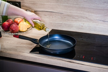 A woman's hand pours oil into a frying pan to cook meat. Cook recipe step-by-step. Pilaf recipe in pictures.